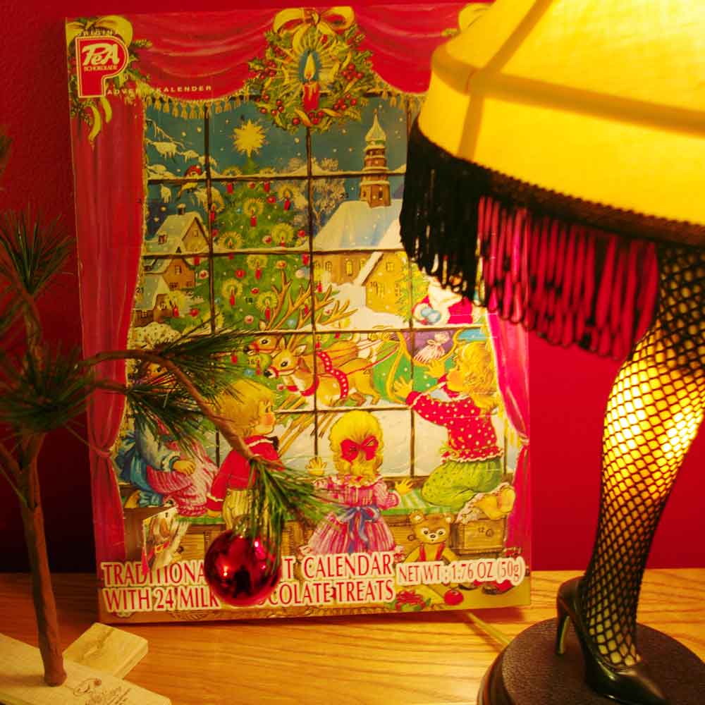 A cardboard advent calendar behind a leg lamp from “A Christmas Story” next to a sad little spindly tree from “A Charlie Brown Christmas.”