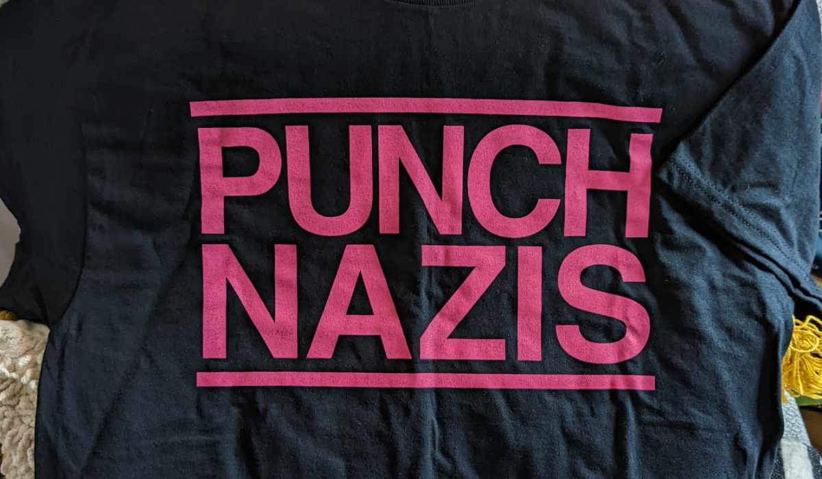 A black t-shirt with bold pink all-caps text that reads ‘PUNCH NAZIS’.