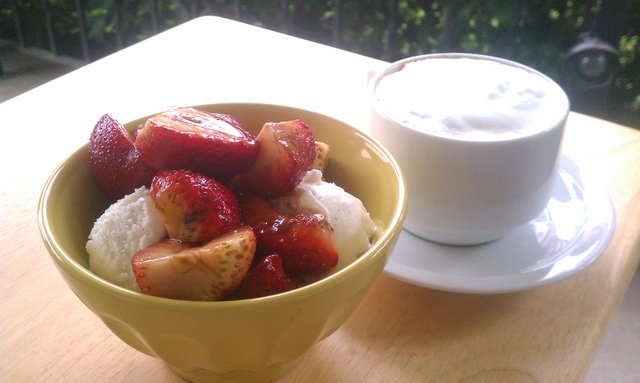 Strawberries tossed with balsamic vinegar over ice cream; cappuccino.