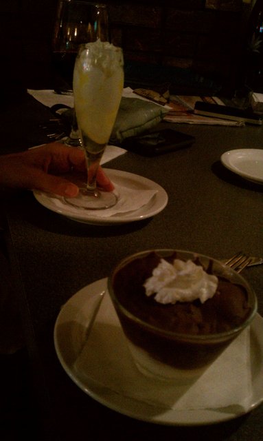 Glass of limoncello sorbet, bowl of profiterol in chocolate and custard.