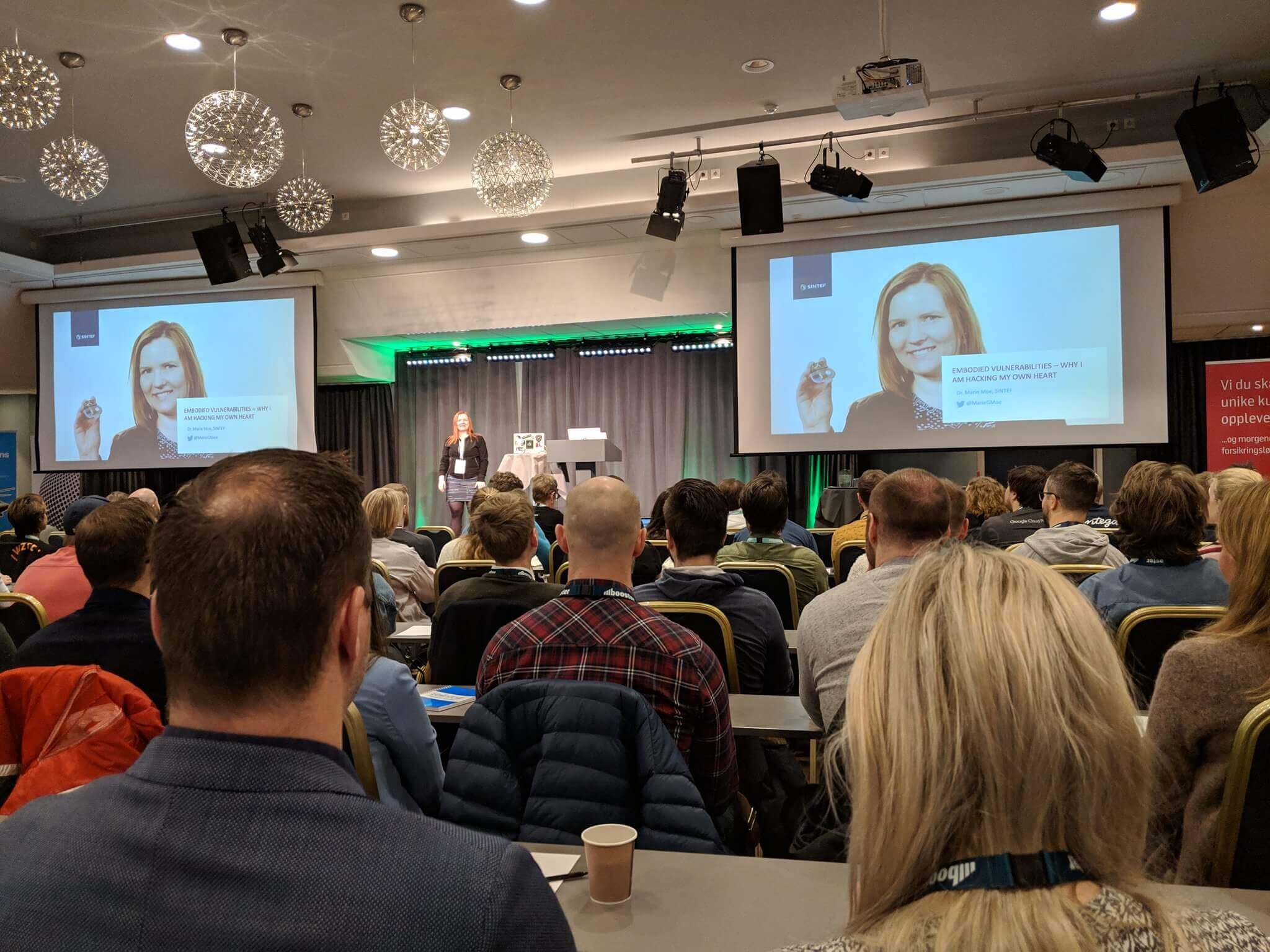 Marie Moe standing on stage in front of an opening slide with her name and photo.