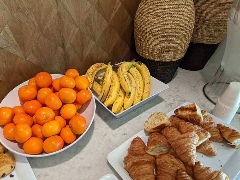Bananas, clementines, and assorted pastries arranged on a table.