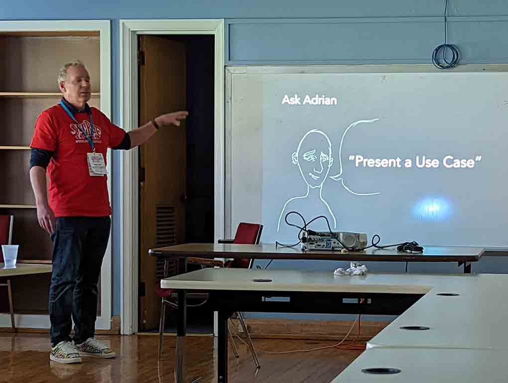 Presenter Ben Dunkle stands in front of a slide with hastily drawn picture of me and a word balloon that reads “Present a use case.”