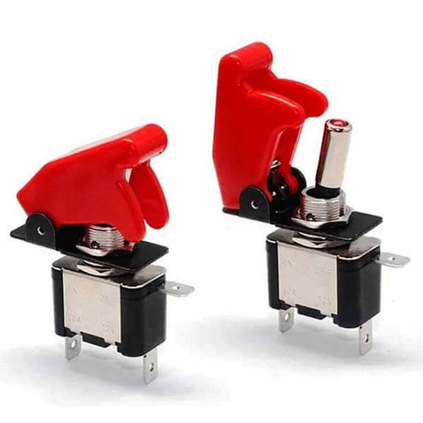 A pair of metal toggle switches, each with a red plastic guard that prevents accidentally flipping the switch and which can be lifted to expose the switch.