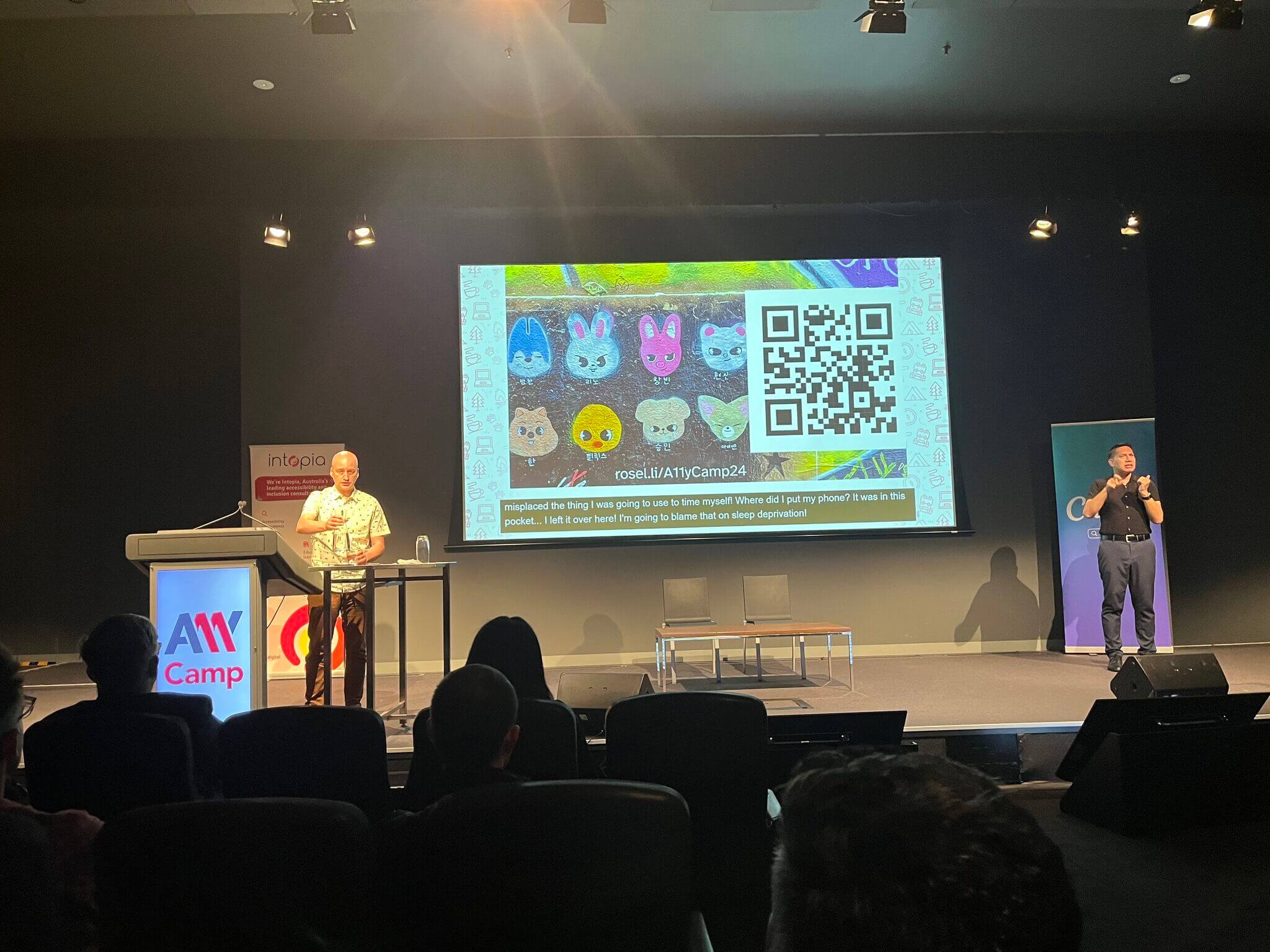 Adrian standing at a lectern in front of his opening slide and its QR code.