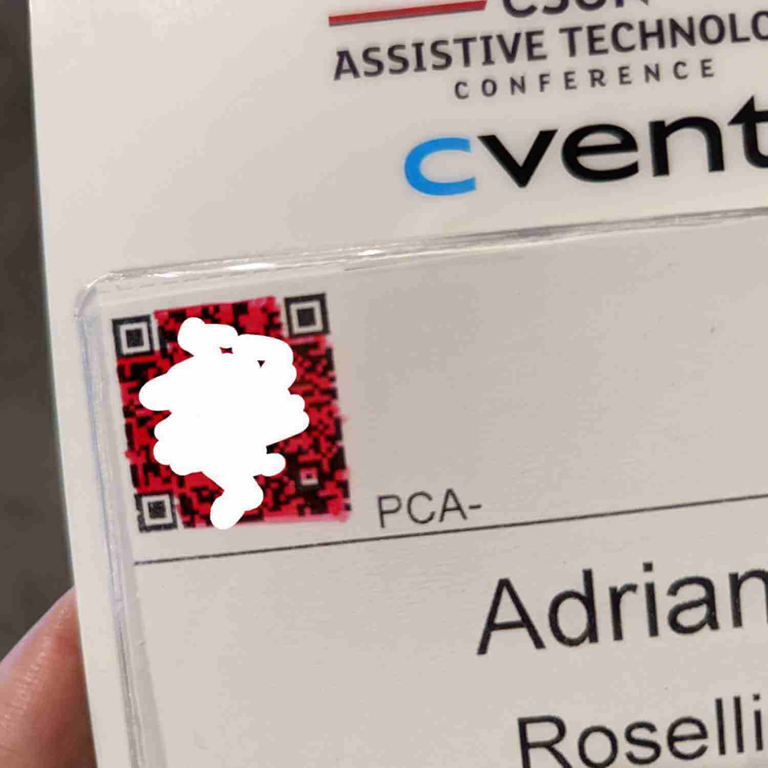 Close-up of my badge with the QR code visible, colored over in red so the black QR code is still visible but the contrast is terrible. I also added white over it in my photo app.